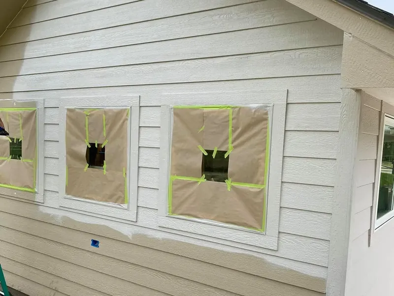Siding prepped for paint with windows masked off, C&A Roofing & Construction