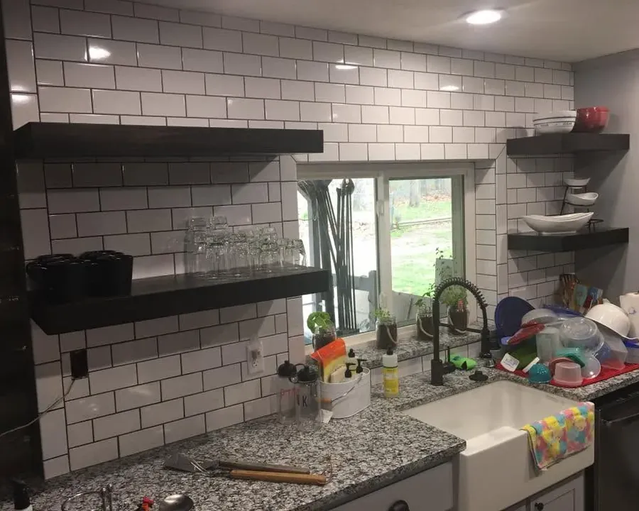 Subway tile backsplash with black floating shelves and farmhouse sink, C&A Roofing & Construction