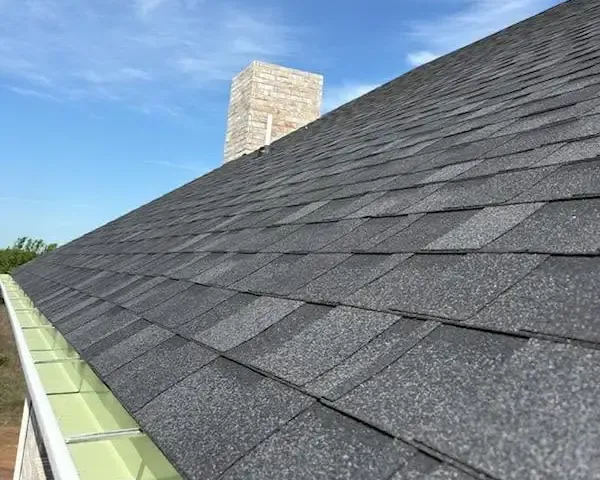 Dark gray shingles along gutter with chimney, C&A Roofing & Construction