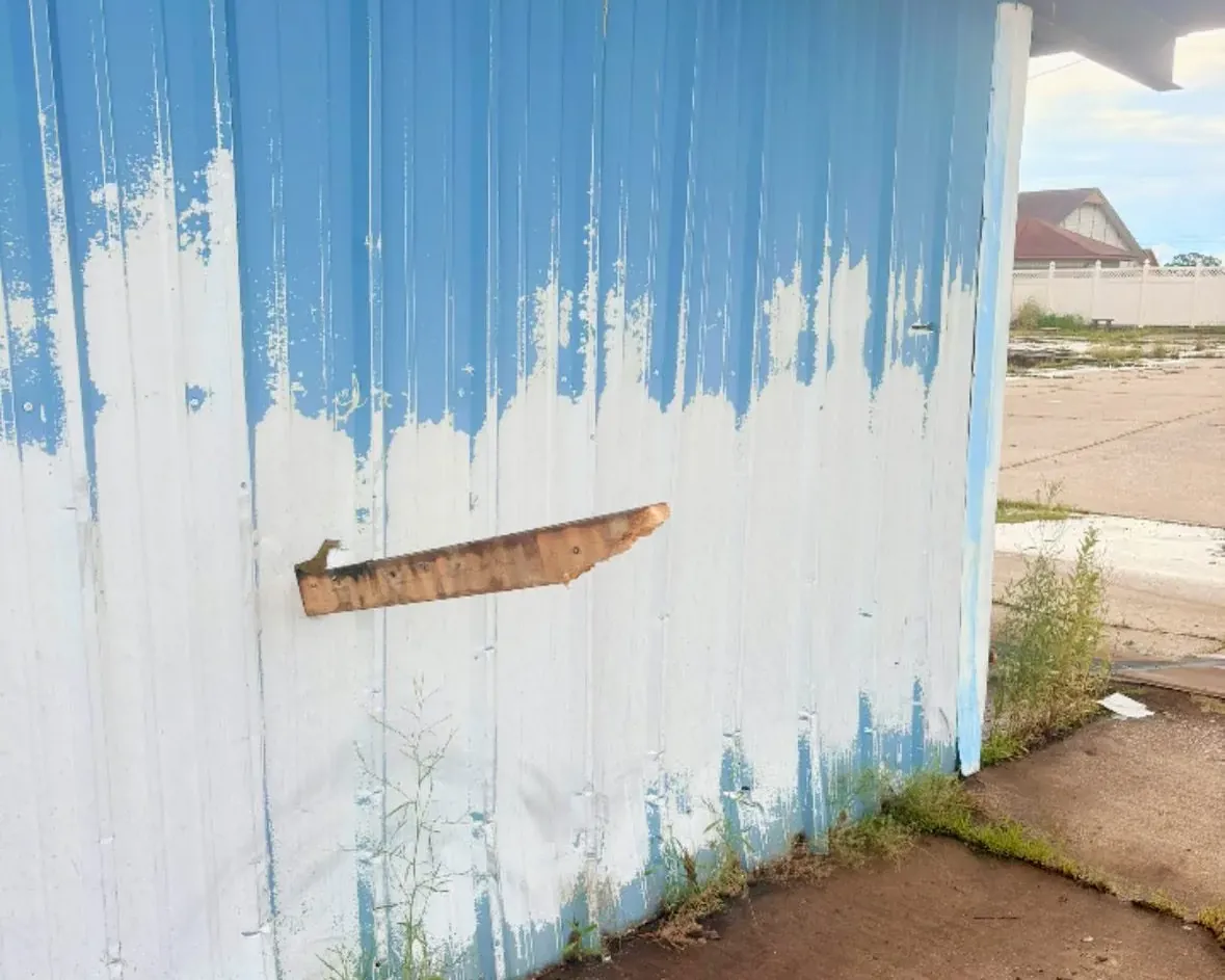 Peeling blue paint on white metal building wall, C&A Roofing & Construction