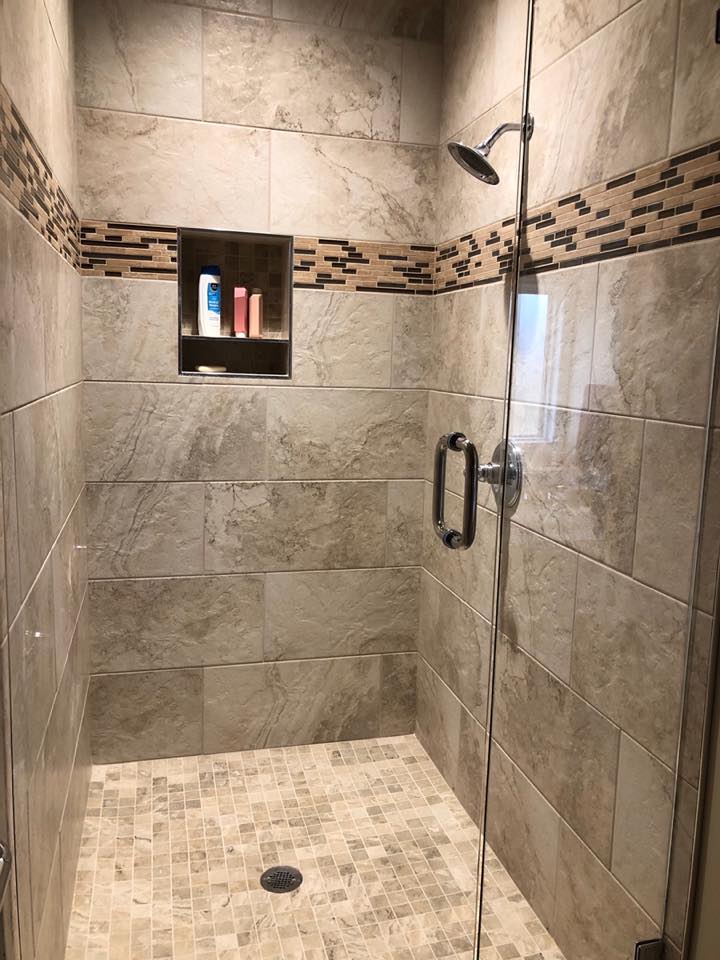 Luxury marble shower with built-in storage niche, mosaic accent border, and premium fixtures by C&A Construction Oklahoma