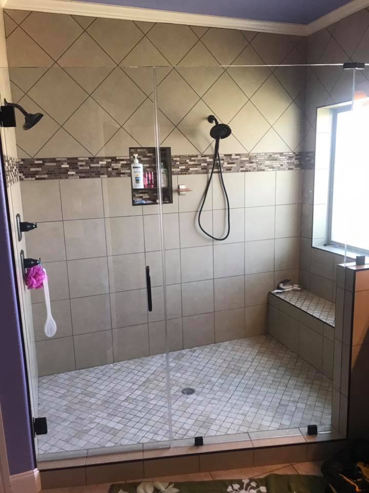 Custom tiled walk-in shower with glass door and bench seat